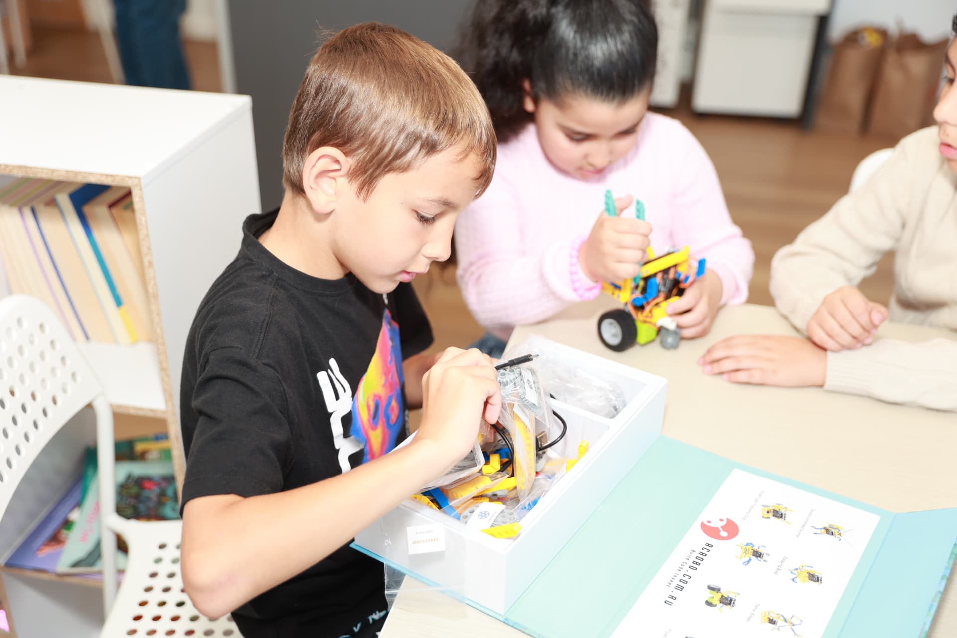 ACROBO students unpacking a robotics kit and assembling a motorised build