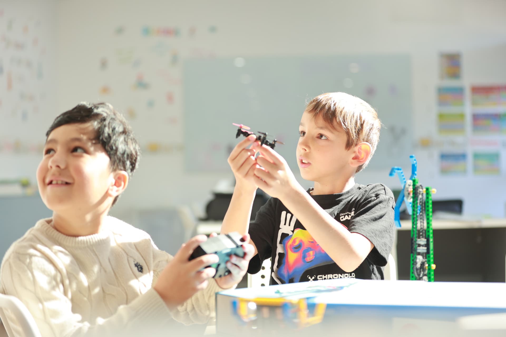 Two ACROBO students flying a small drone in class, one holding the controller